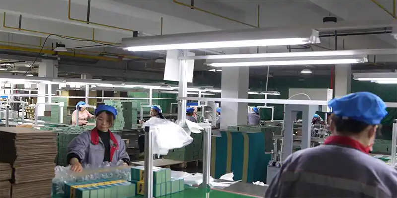 Factory floor with manual collapsible box assembly line, workers at multiple stations